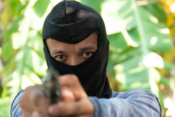 istock Select focus of crime eyes. Robber in black ski mask aims with gun 1152640887
