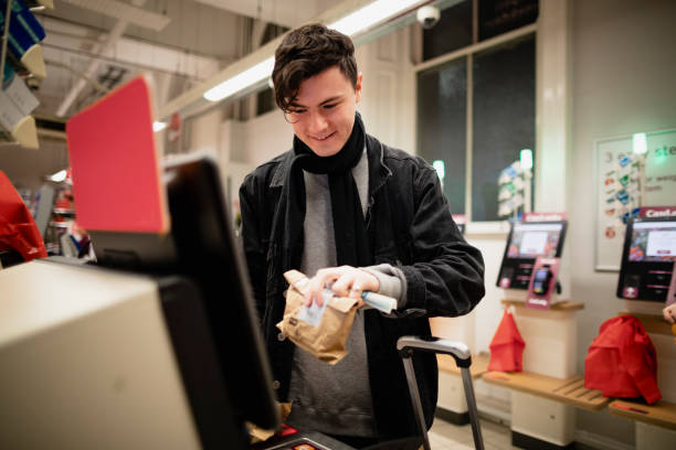 Using the Self Check-Out Young male adult smiling while using a self-service checkout machine while in a supermarket. self checkout stock pictures, royalty-free photos & images