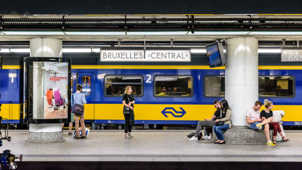 passagiers wachten op een platform in brussel centraal station terwijl een nederlandse trein is stationing. - ns stockfoto's en -beelden