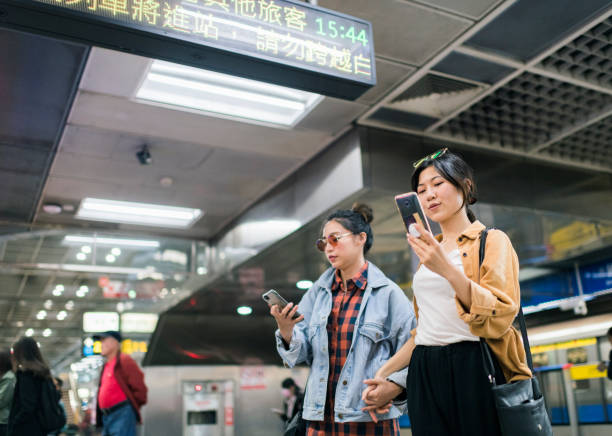 istock Two young women checking their phones standing on subway platform 1152643816