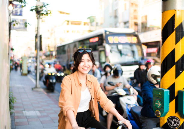 istock Young woman smiles to camera waiting at intersection on her bicycle 1152644119
