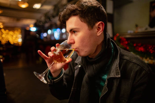 Enjoying a Drink at Christmas Young male adult sitting in a bar/ pub drinking a large glass of white wine. His little finger is extended, showing his elegance. pinky finger stock pictures, royalty-free photos & images