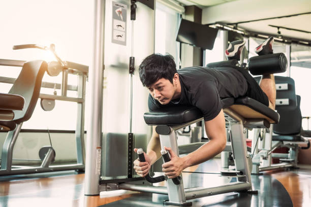 istock Asian sport man stretching and lifting weight by two legs when facing down for stretching muscle at fitness gym at condominium background. Sport and People lifestyles concept. Leg curl posture 1152647096