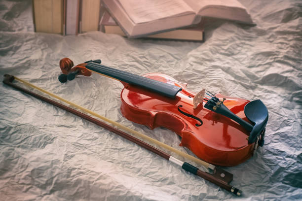istock The abstract art design background of classic violin and bow put in front blurred book stacked,on background,blurry light around 1152647486