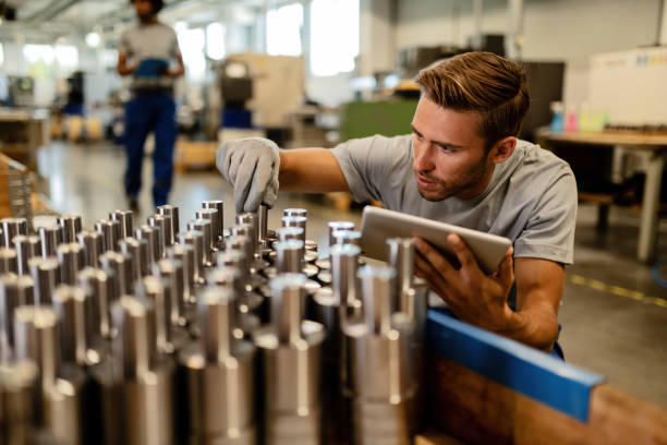 giovane operaio siderurgico che esegue il controllo di qualità dei prodotti fabbricati in un magazzino. - quality inspection foto e immagini stock