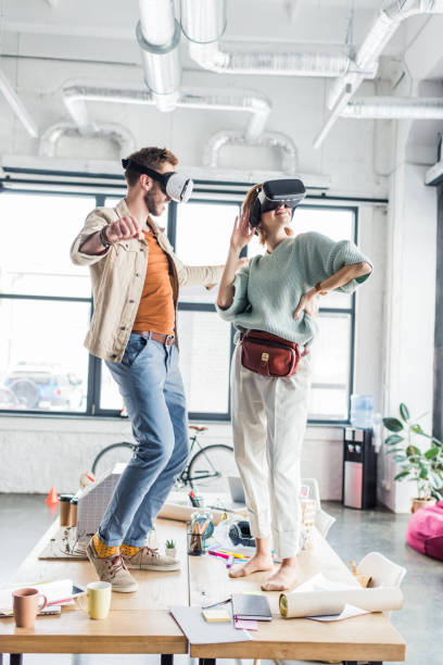 istock female and male architects wearing vr headset, gesturing with hands and having virtual reality experience in loft office 1152651551