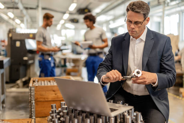 istock Quality control inspector measuring steel rod with a caliper while using laptop in a factory. 1152652864