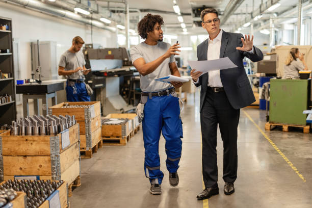 istock Mid adult engineer and African American worker communicating while walking through factory plant. 1152653049