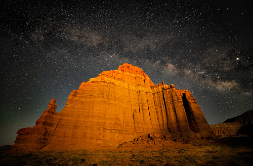 Setting moon lights up face of the Temple of the Moon in Cathedral Valley, Capital Reef National Park, with the Milky Way arcing overhead