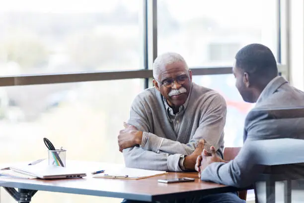 Photo of Unrecognizable banker takes time to visit with senior customer