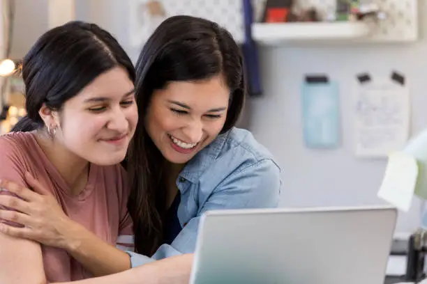When they search the college web site and realize the daughter has been awarded a scholarship, the Hispanic mother and daughter celebrate.