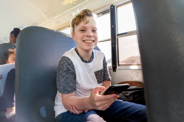 istock Boy on bus looks up from phone to smile 1152655125