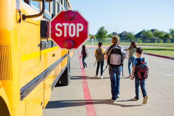 el equipo de seguridad mantiene a los niños seguros mientras caminan hacia el autobús - autobús de colegio fotos fotografías e imágenes de stock