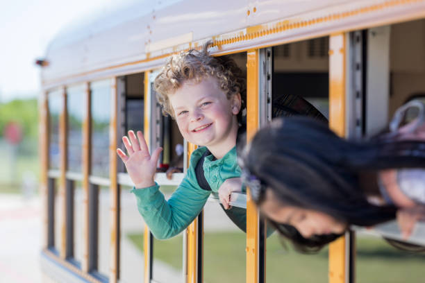 istock Cute little boy waving from a school bus 1152655384