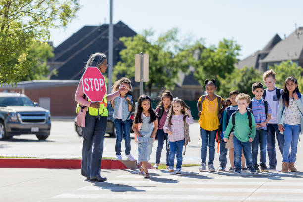 cruzar guardia ayuda a los niños a cruzar la calle - crossing guard fotografías e imágenes de stock