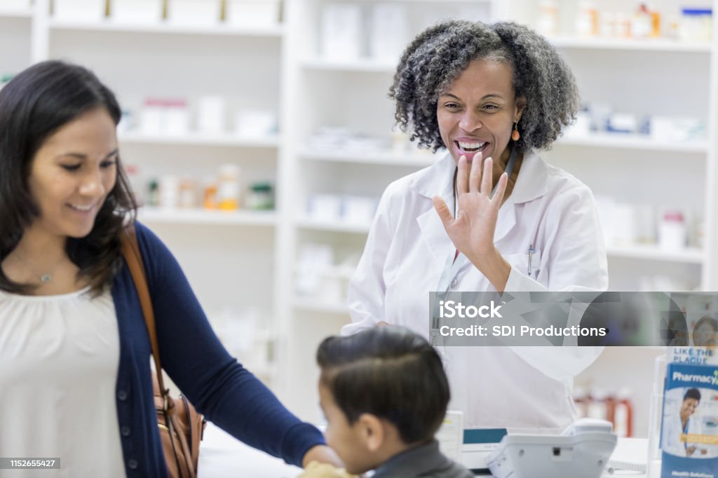 満足の顧客は薬剤師の波として薬局を離れる - 立ち去るのロイヤリティフリーストックフォト