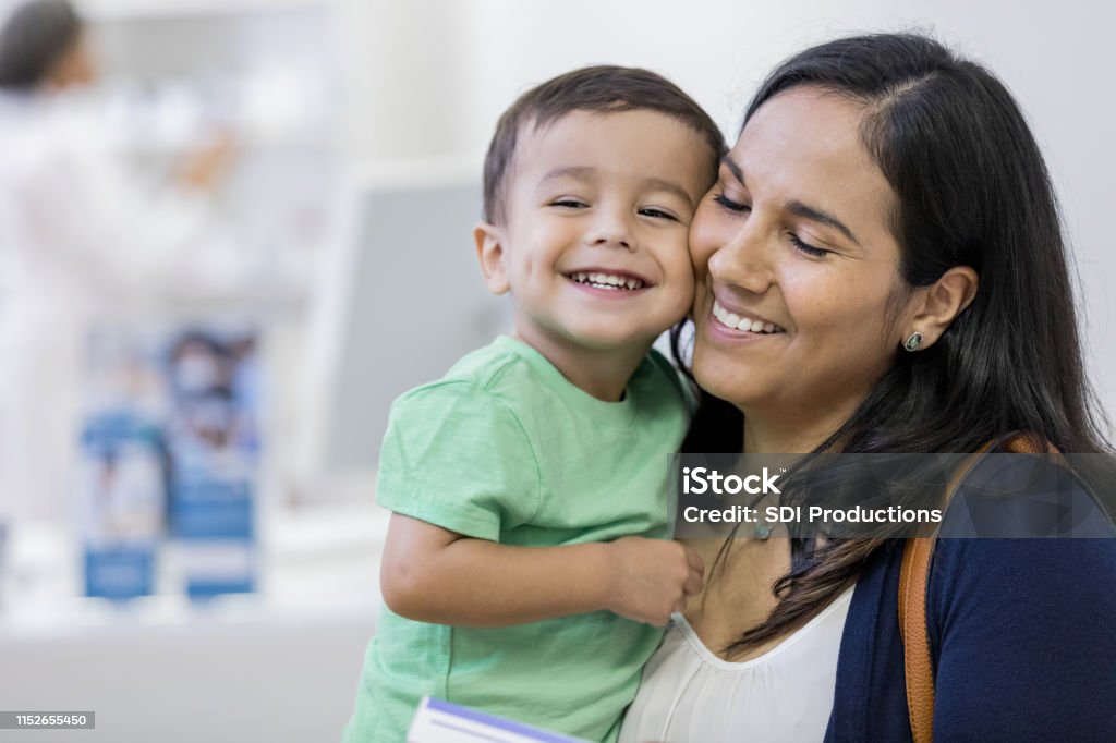A mother and her child embrace lovingly at store A toddler smiles as he presses cheeks with his mother at the store. His mother smiles and closes her eyes contentedly. Child Stock Photo