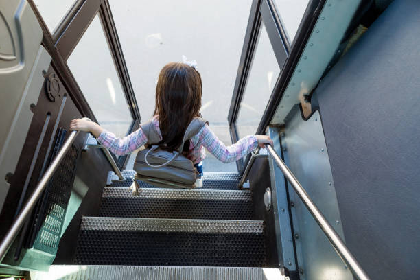 la chica de la escuela primaria se descarga cuidadosamente del autobús escolar - bus door fotografías e imágenes de stock