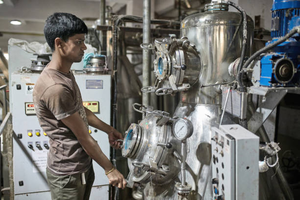 Close-up of skilled Indian factory worker operating large and complex machinery used in the dyeing of textiles.