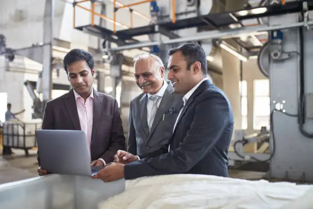 Indian CEO and senior managers meet on the factory floor to examine manufacturing methods and ensure quality control.