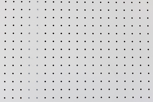 orderly dot or holes rows and columns on white pegboard wall.
