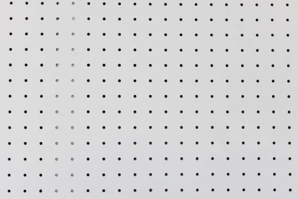 orderly dot or holes rows and columns on white pegboard wall. stock photo