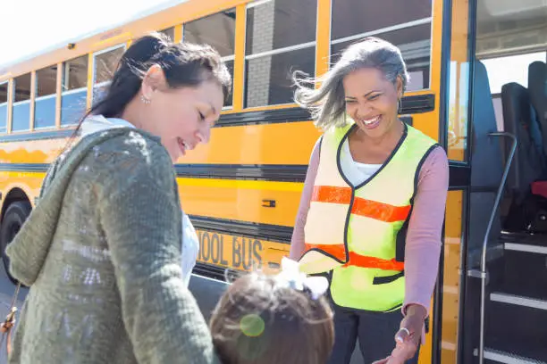 Photo of A Bus driver and a mother smile at schoolgirl