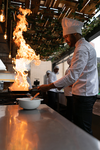 Latin American chef cooking at a restaurant making things on flambe - food and drinks concepts