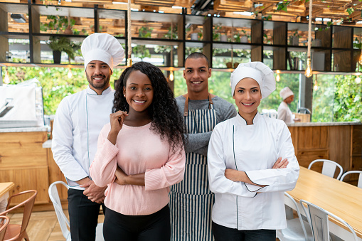 Happy African American business owner with her staff working at a restaurant and looking at the camera smiling