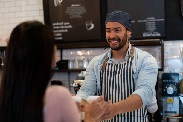 istock Happy waiter serving coffee to a customer at a cafe 1152658709