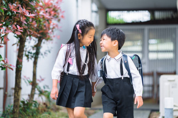 A two elementary school kids are leaving home for school hand in hand.