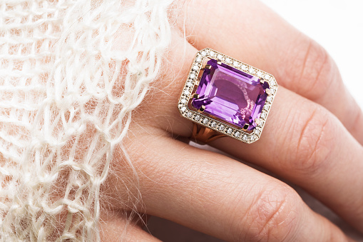 Beautiful golden ring with a large amethyst on a female hand, close-up