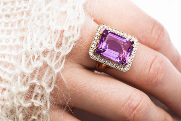 Beautiful golden ring with a large amethyst on a female hand, close-up stock photo