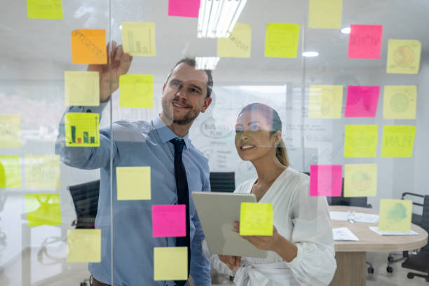 istock Latin american business partners brainstorming ideas using adehsive notes and a tablet both smiling 1152666351