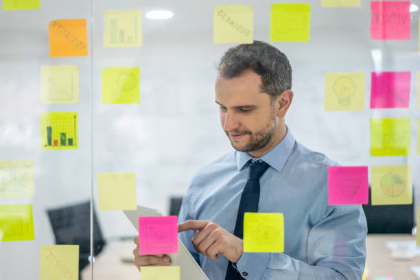 istock Handsome man planning a business strategy using adhesive notes on glass window 1152667917