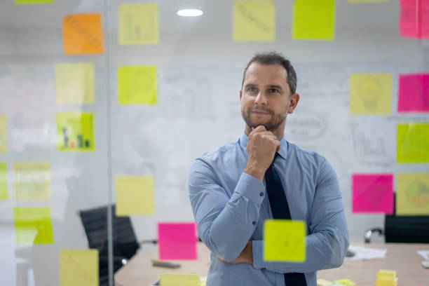 istock Thoughtful businessman looking at adehsive notes on window planning a business strategy 1152667918