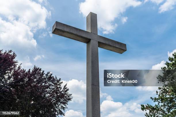 A Large Concrete Cross On A Cemetery Against A Blue Sky With White Clouds Stock Photo - Download Image Now