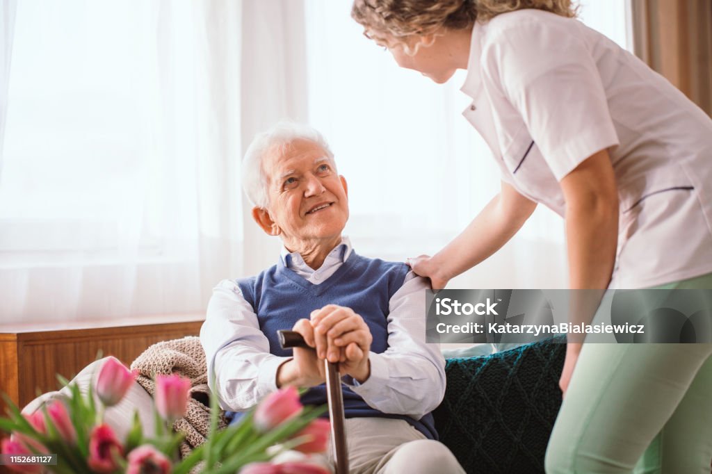 Senior man with a walking stick being comforted by nurse in the hospice Senior Adult Stock Photo
