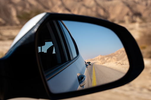 Rearview mirror picture reflecting a road in the desert