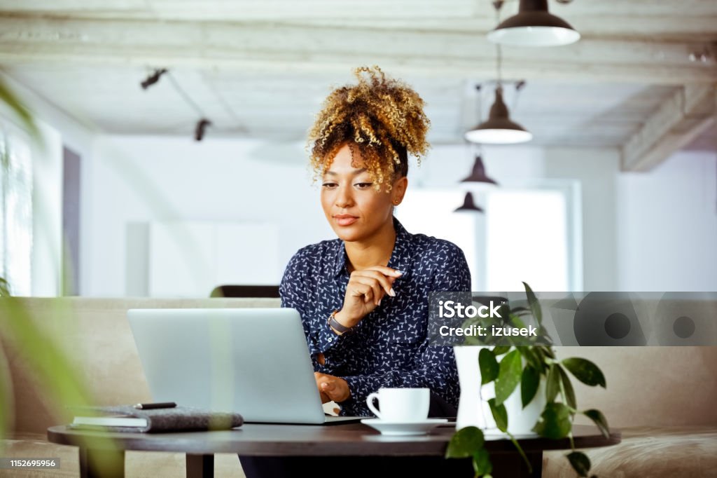 Skilled female worker looking at laptop in office Skilled female white collar worker looking at laptop in office. Business executive is with confident look on her face. She is related to financial occupation. Financial Advisor Stock Photo