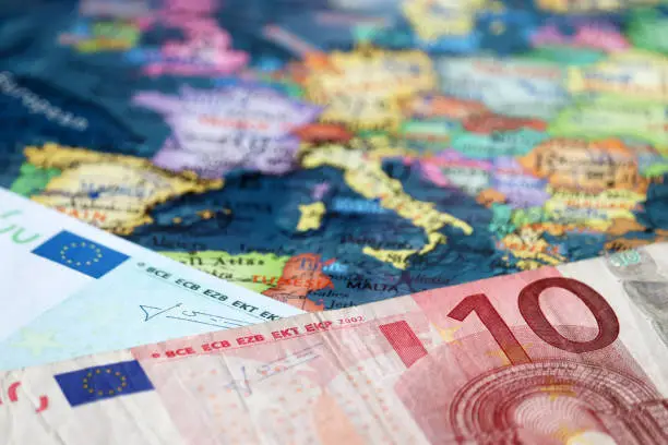 Photo of Euro banknotes on the map of Europe, selective focus. Concept for european economy, eurozone countries