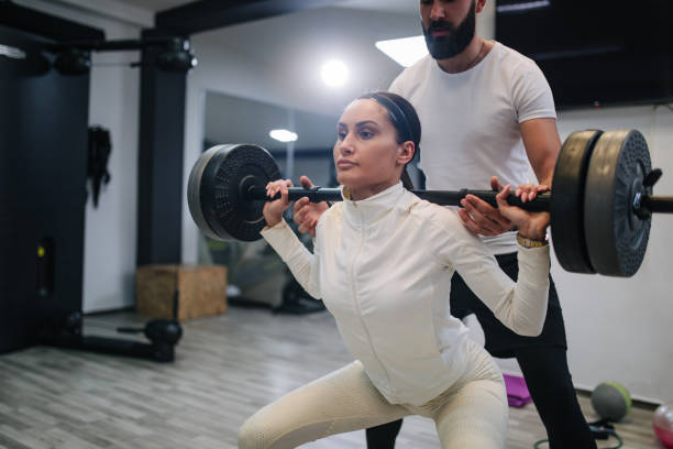 istock Sporty young couple doing squat exercise in gym 1152699913