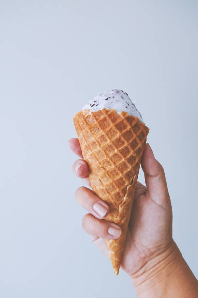 istock Female hand fingers hold a waffle cone with ice cream 1152705912