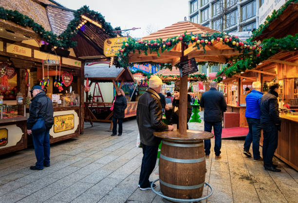 Tourists at Christmas market with Gluhwein at Memorial Church Berlin, Germany - December 11, 2017: Tourists at Christmas market with Gluhwein hot wine and candiesin Germany in Europe in winter. Kaiser Wilhelm Memorial Church, Berlin. kaiser wilhelm memorial church stock pictures, royalty-free photos & images