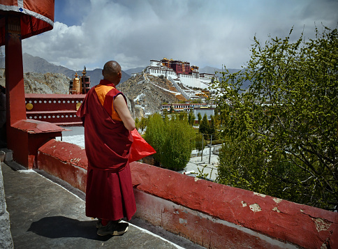 Tibetan monk in traditional dress, overlooks The Potala Palace (one time residence of the Dalai Lama) from a nearby monastery in Lhasa, the capital city of Tibet.