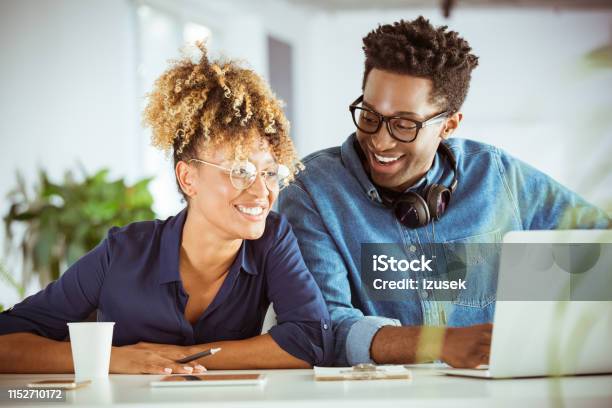 Smiling Professionals Discussing Over Laptop Stock Photo - Download Image Now - 30-34 Years, Adult, Adults Only