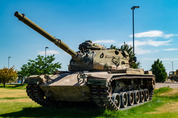 Three military tanks positioned on lush green grass, showcasing their powerful presence under a cloudy sky. Ideal for military-themed visuals.