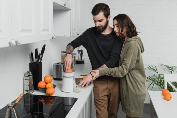 istock beautiful young couple preparing orange juice during breakfast in kitchen 1152714523