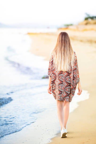 istock young woman walking on the beach at sunset 1152722517