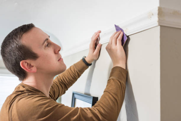 Young man sanding nail holes on white trim board Man hand sands nail filling to install white wood trim crown moulding moulding trim photos stock pictures, royalty-free photos & images
